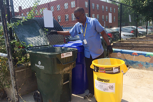 Janitorial staff looking into compost bin outside
